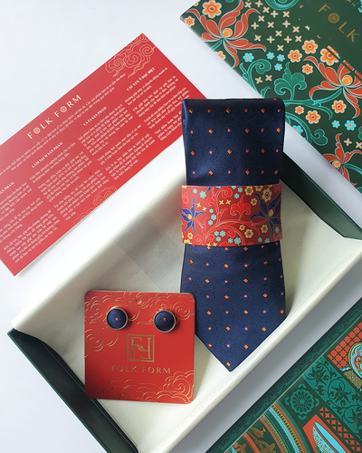 Navy dotted silk tie with matching round cufflinks on a red card, in an open gift box