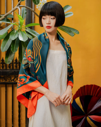 Woman wearing a Folk Form Dragon Dreams Vietnamese silk scarf in dark green and orange, draped over the shoulders