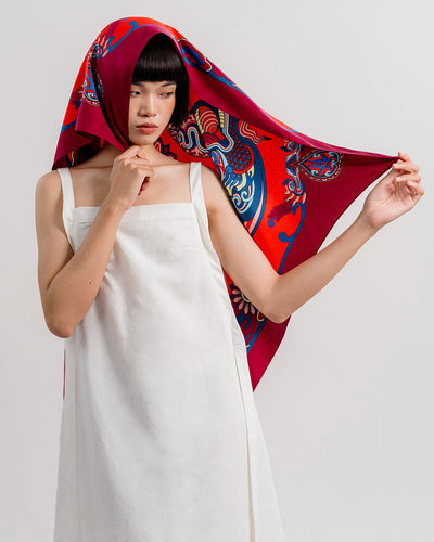 Red Dragon Dreams silk scarf worn over the head, one corner held out to show the dragon