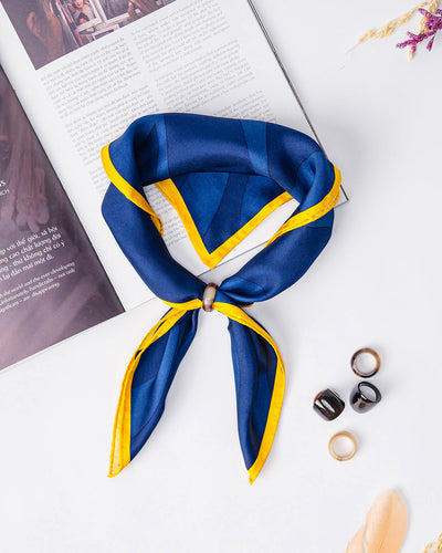 Navy and yellow Peace in Mind silk scarf, 22 inch square, knotted through a scarf ring, flat lay