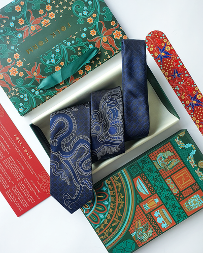 Navy silk jacquard tie with a woven dragon pattern, folded in an open gift box