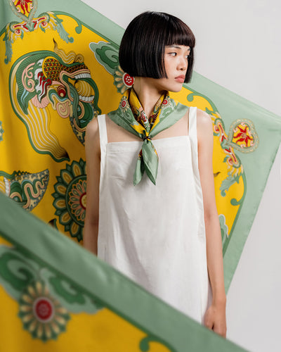 Green and yellow Dragon Dreams silk scarf folded into a band and knotted at the front of the neck