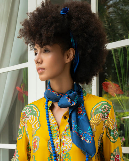 Navy silk scarf tied in a soft neck bow over a yellow shirt