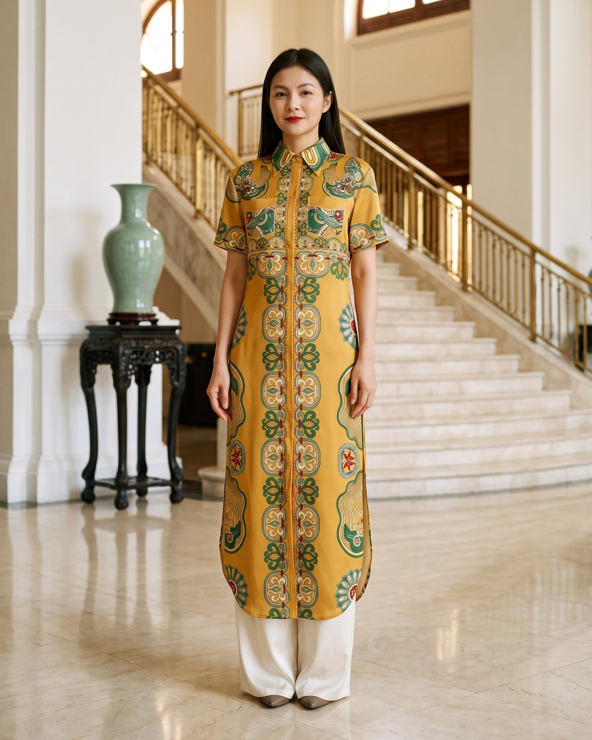 Woman wearing a mustard-gold silk ao dai with hand-printed green dragon motifs in the entrance hall of an Indochine fine-arts museum