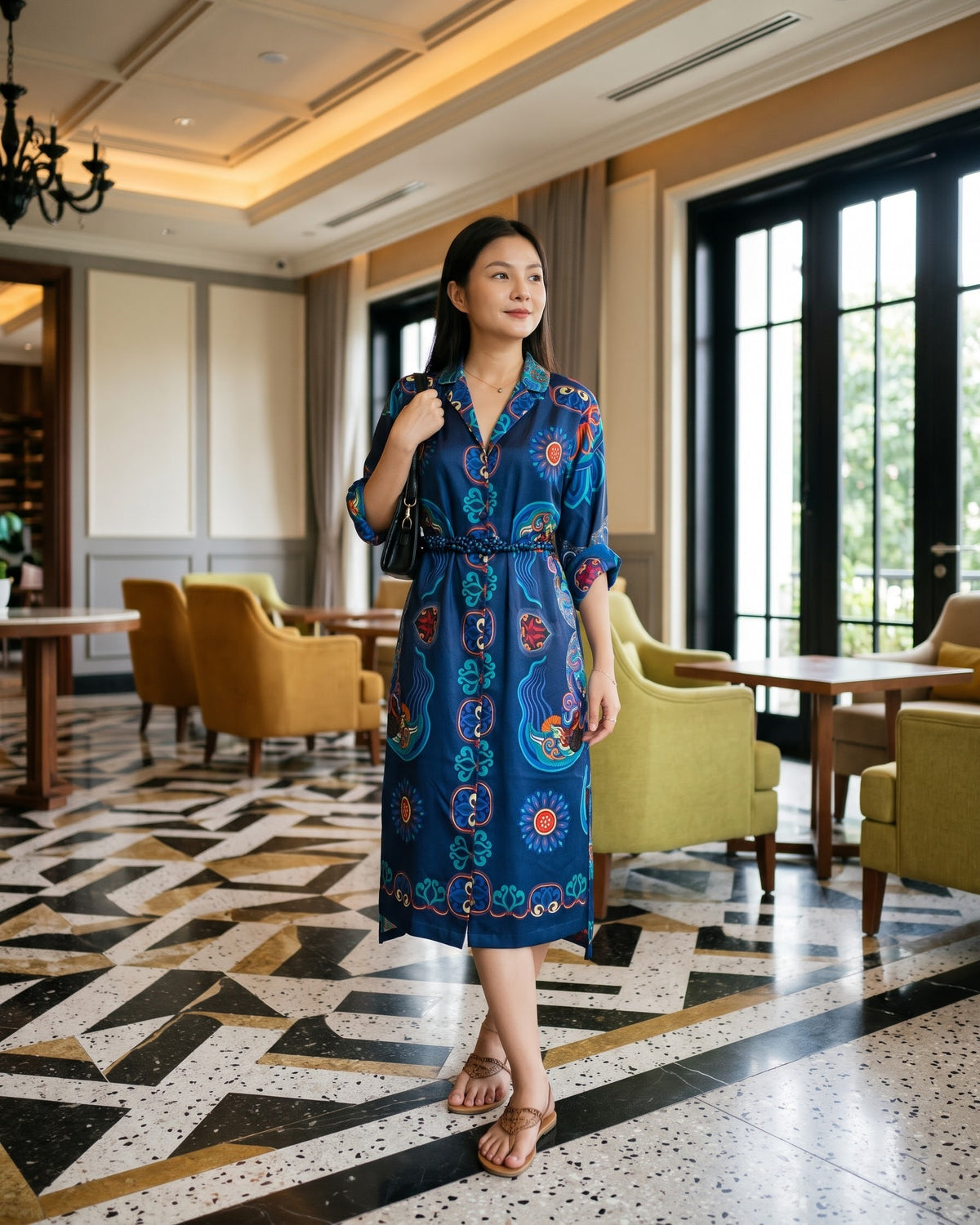 Navy blue silk wrap shirt-dress with hand-printed dragon and wave motifs and a braided belt, worn in a hotel tea lounge